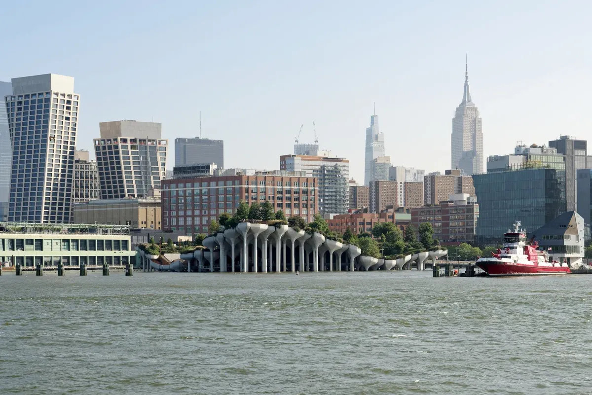 Little Island at Pier 55, the tulip-pot park on the Hudson, with the Empire State Building and Hudson Yards-area towers behind and a red fireboat at right, seen on a New York architecture boat tour