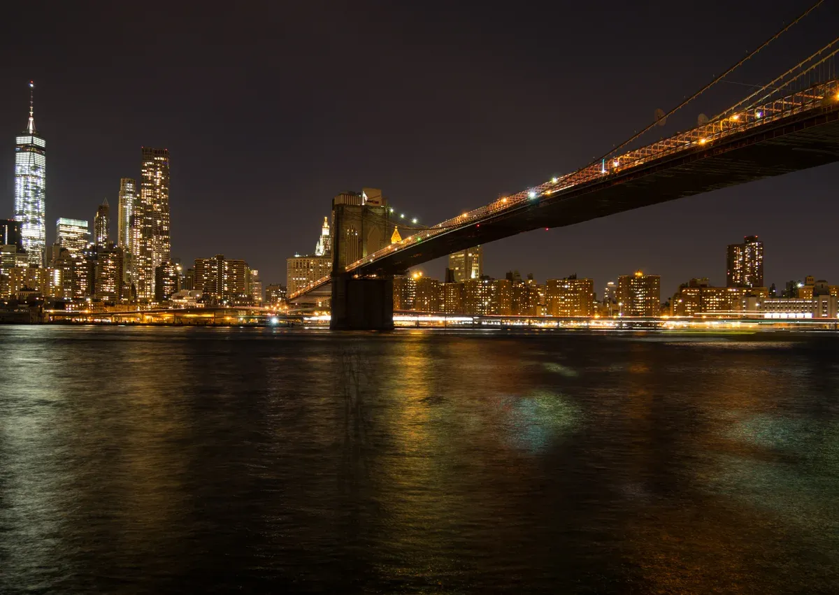 Brooklyn Bridge lit at night over the East River, the view on a New York architecture boat tour