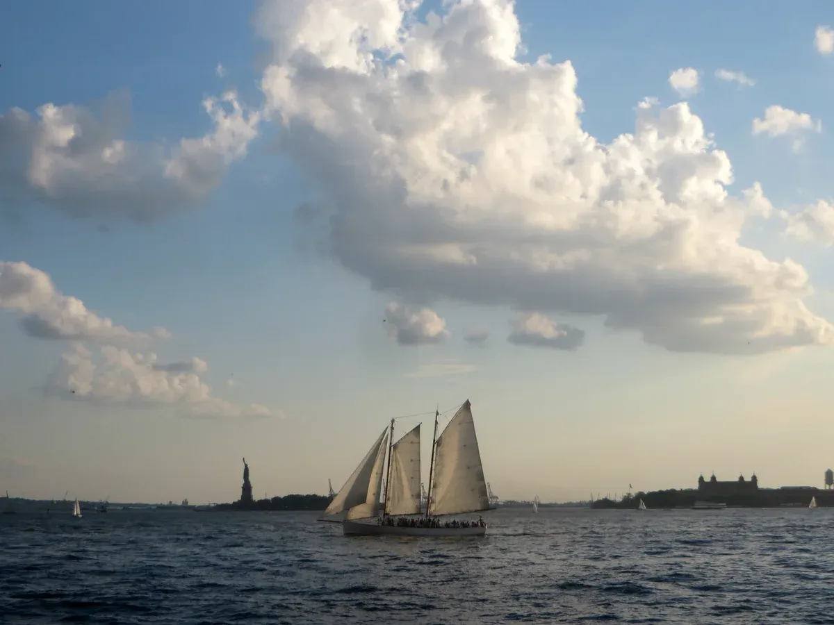 Schooner under sail in New York Harbor with the Statue of Liberty behind, like an architecture boat tour in New York