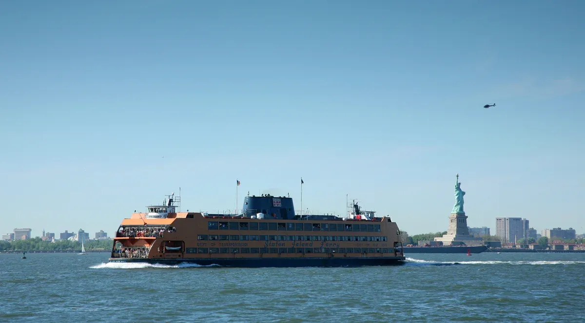 The Staten Island Ferry Andrew J. Barberi crossing New York Harbor with the Statue of Liberty in the background, part of a New York architecture boat tour