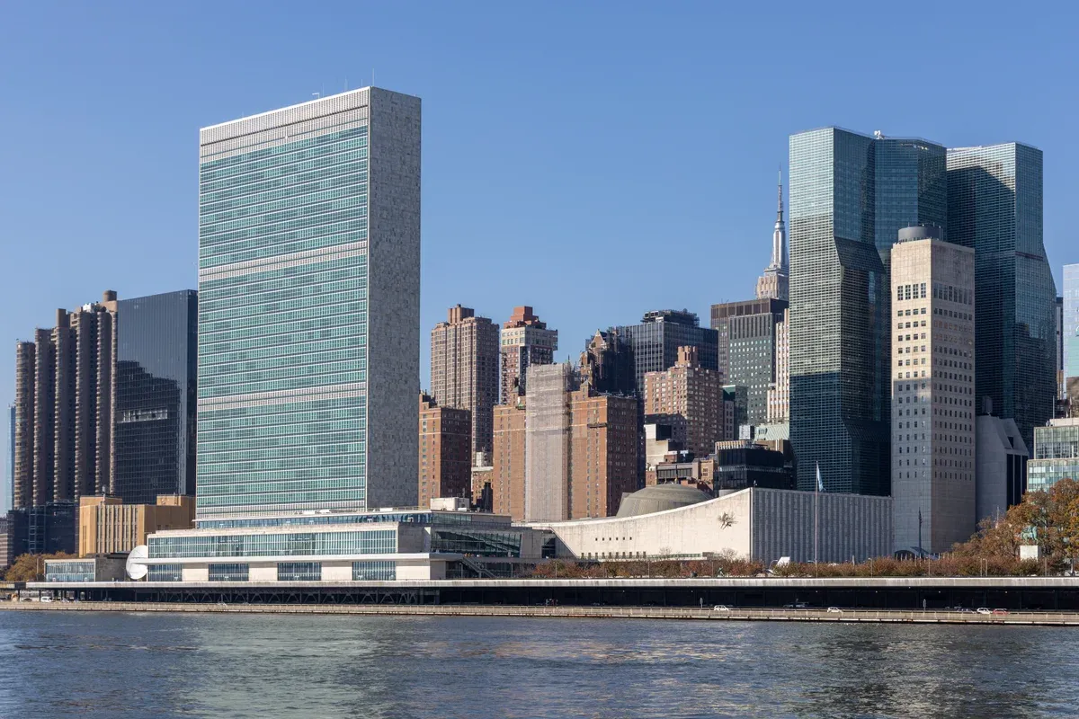 The United Nations Headquarters Secretariat tower and General Assembly building on the East River shore, with the Midtown skyline beside it, seen on a New York architecture boat tour